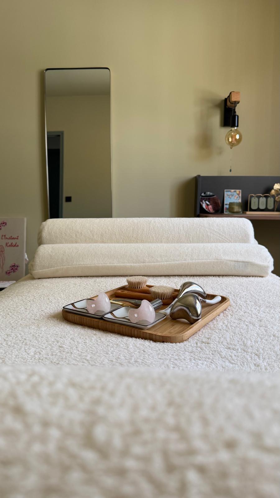 La table de massage et son plateau d'accessoires, devant le miroir de la cabine.